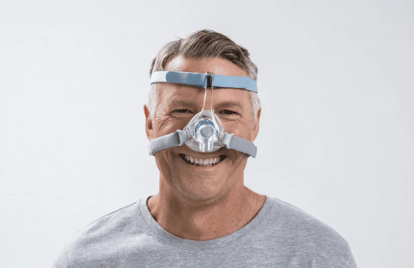 Man wearing a CPAP mask on a plain background